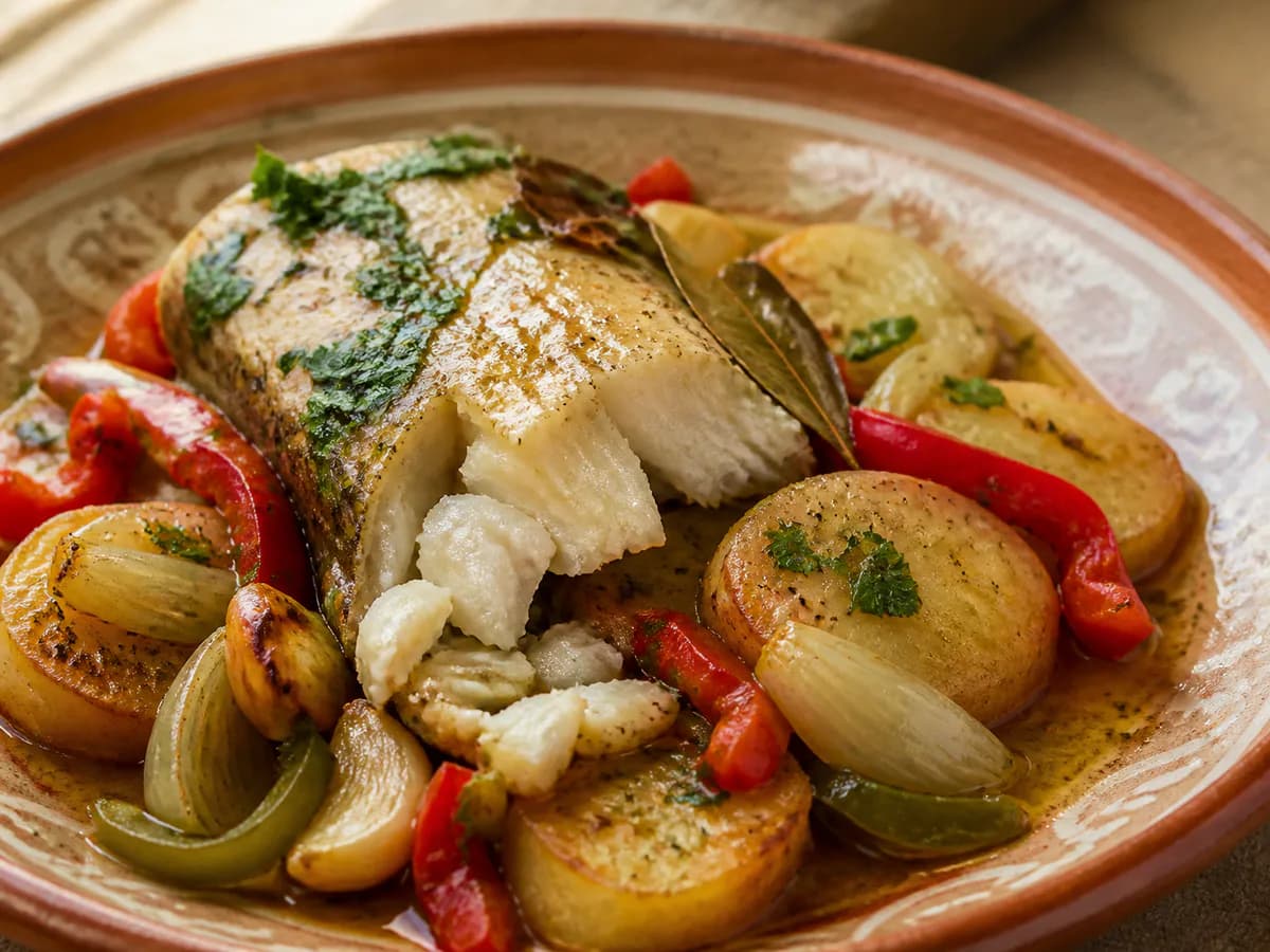 Pormenor de uma porção de Pescada Assada no Forno com Batatas e Legumes