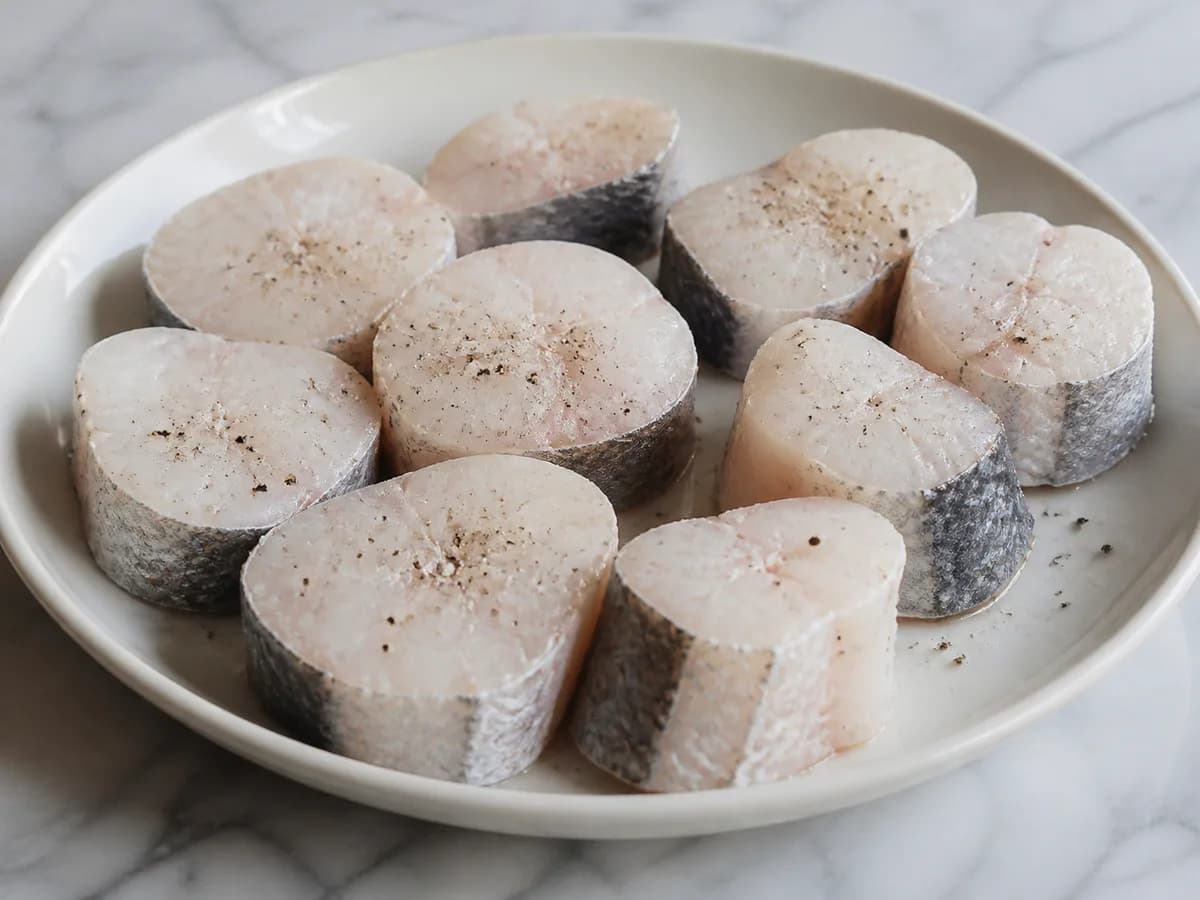 Preparação de Pescada Assada no Forno com Batatas e Legumes durante a confeção