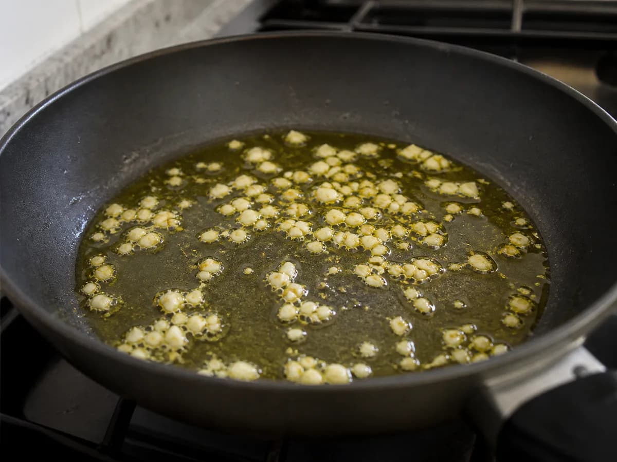 Preparação de Alheiras no Forno com Espinafres Salteados, Ovo Estrelado e Batata Frita durante a confeção