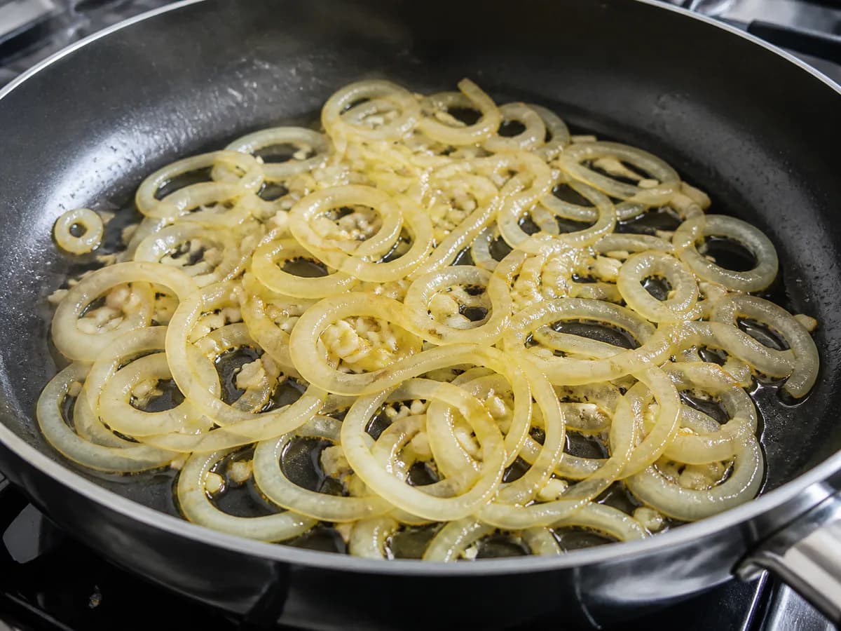 Preparação de Postas de Bacalhau Fritas com Cebolada durante a confeção