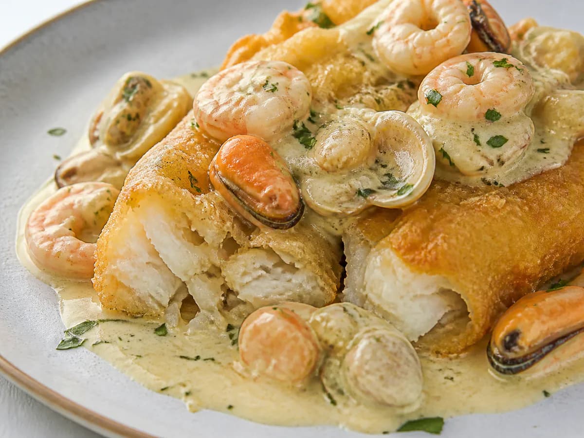 Pormenor de uma porção de Bacalhau Frito com Molho de Frutos do Mar