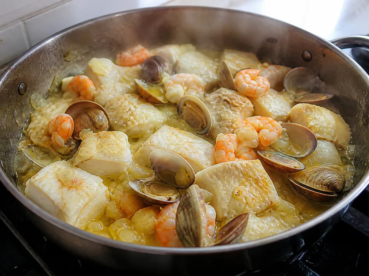 Preparação de Bacalhau no Forno com Batatas, Camarão e Ameijoas durante a confeção