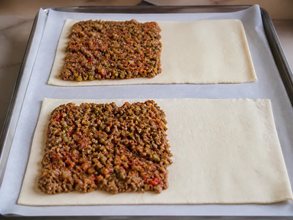 Preparação de Rolinhos de Massa Folhada com Carne Picada durante a confeção