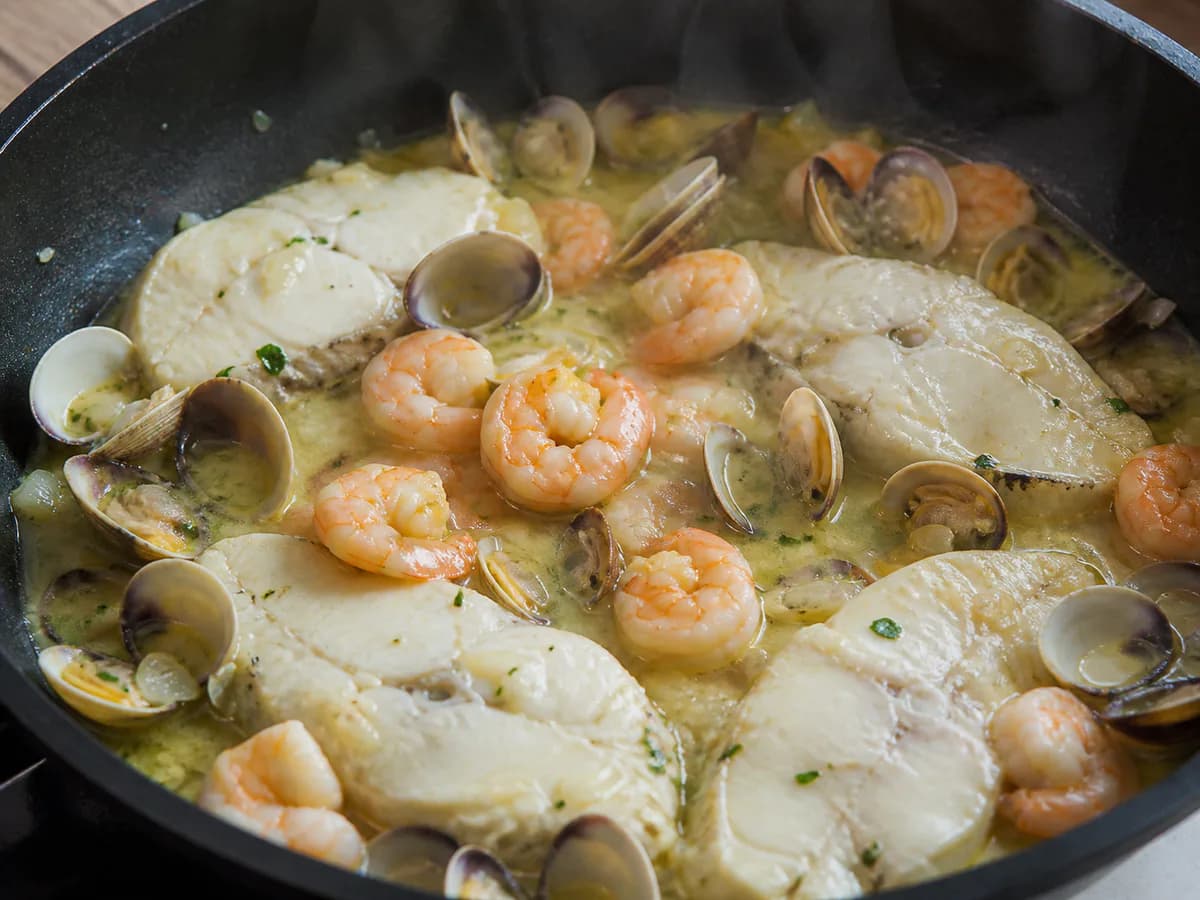 Preparação de Pescada com Molho de Ameijoas e Camarão durante a confeção