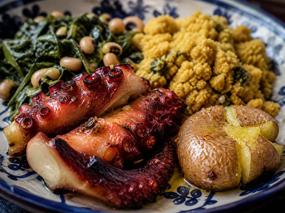 Pormenor de uma porção de Polvo à Lagareiro com Migas de Broa de Milho, Grelos e Feijão Frade e Batatas a Murro